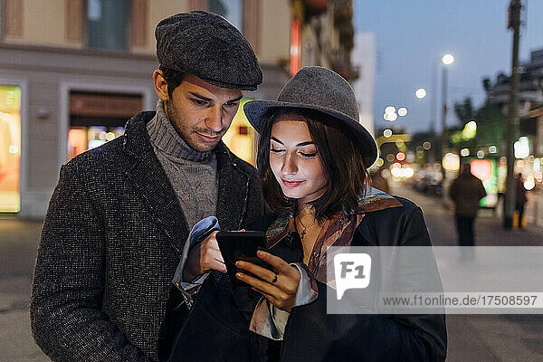 Girlfriend and boyfriend using mobile phone together in city