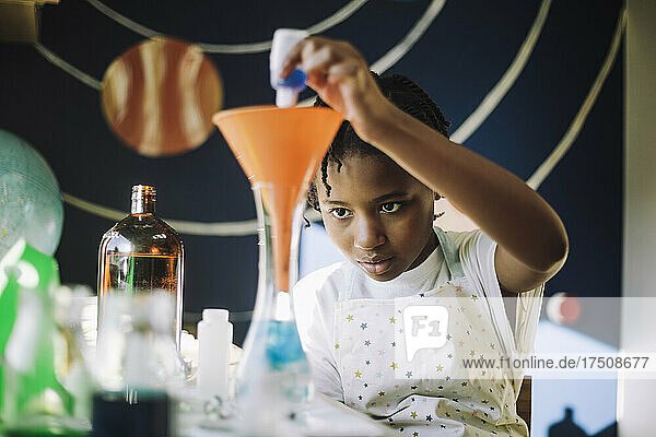 Ehrgeiziges Mädchen  das eine chemische Lösung mischt  während es ein wissenschaftliches Projekt am Tisch lernt