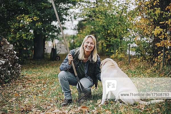 Portrait of smiling woman with dog in backyard