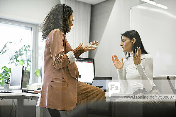 Female boss discussing with colleague over computer in office