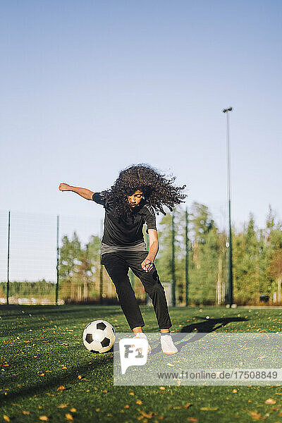 Mädchen spielt Fußball auf einem Sportplatz an einem sonnigen Tag