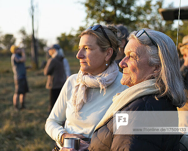 Zwei Menschen  eine reife Frau und ihre Mutter  stehen bei Sonnenuntergang nebeneinander