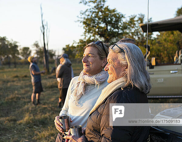 Two people  a mature woman and her mother  standing side by side at sunset