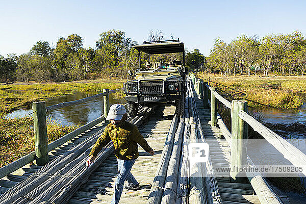 Ein Junge geht über eine Holzbrücke über ein Sumpfgebiet.