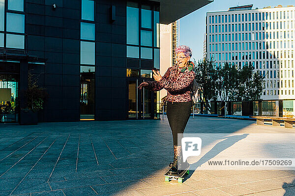 Italy  Fashionable senior woman standing on skateboard  holding smart phone