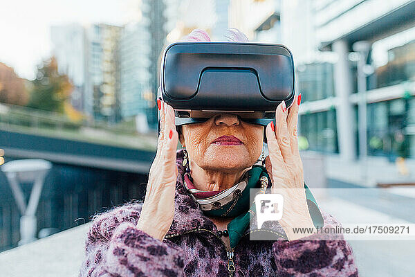 Italy  Fashionable senior woman with VR goggles in city