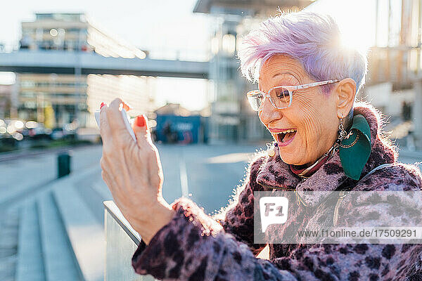 Italy  Smiling fashionable senior woman with smart phonein city