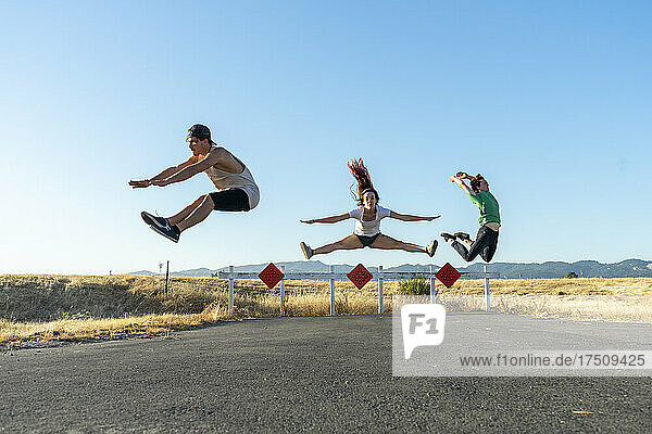 Three acrobats jumping mid-air