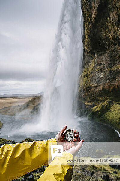 Iceland  Seljalandsfoss Waterfall  woman's hand holding compass
