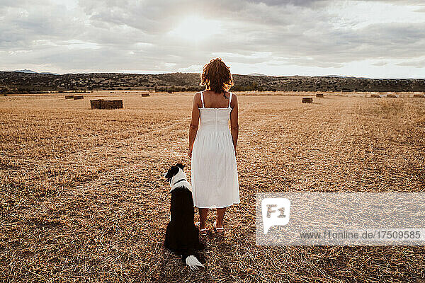 Woman standing by dog in field
