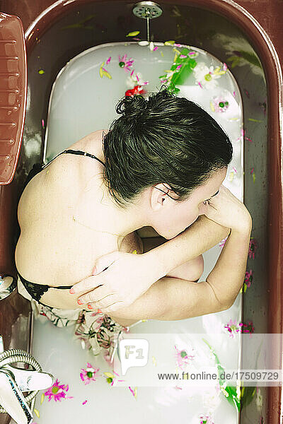 Woman taking a milk bath with blossoms