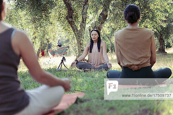 Drei Menschen meditieren im Park