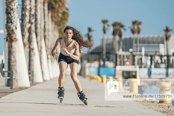 Young woman inline skating on promenade at the coast