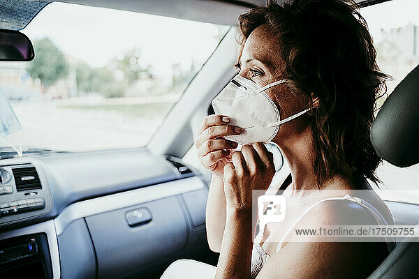 Frau trägt während COVID-19 eine schützende Gesichtsmaske im Auto