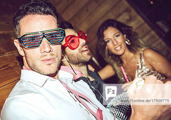 Young man wearing shutter shade while enjoying with friends in party