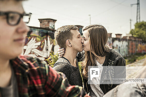 Teenage couple kissing in an old run down industrial area
