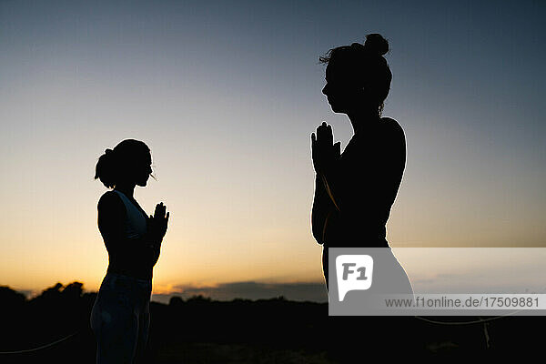 Silhouette of women in prayer position outdoors
