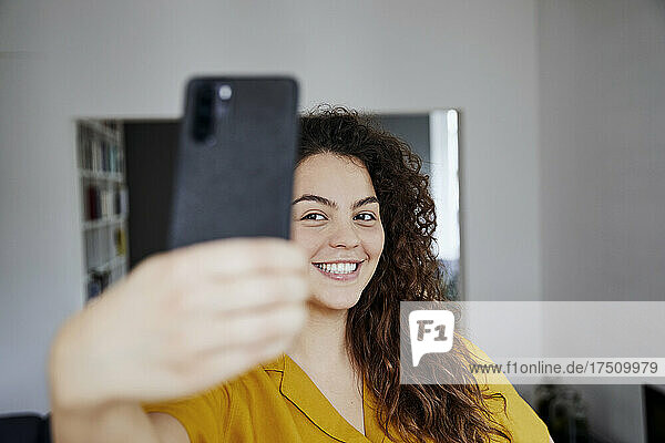 Happy young beautiful woman taking selfie at home