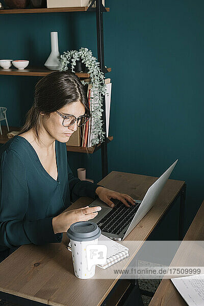 Junge Frau benutzt Laptop auf Schreibtisch zu Hause
