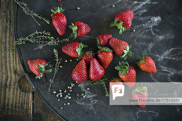 Thyme  peppercorn and fresh strawberries on rustic baking sheet
