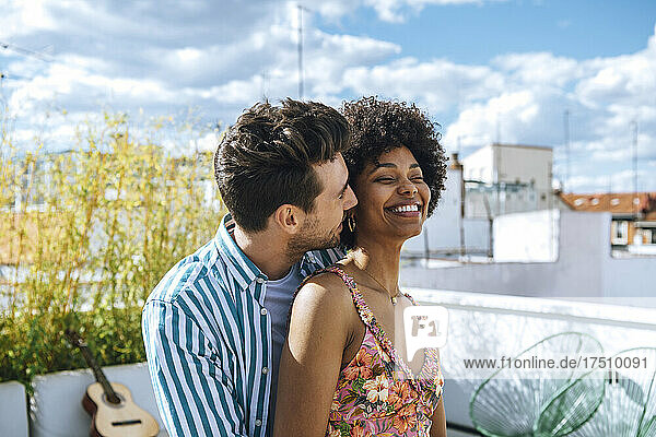 Happy multi-ethnic couple spending quality time on penthouse patio
