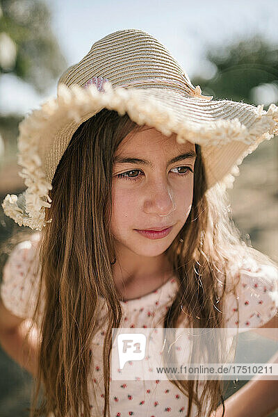 Cute girl wearing hat while looking away in farm