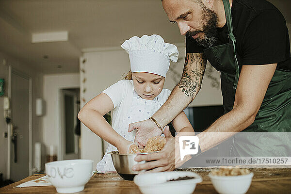 Father and daughter baking cookies at home