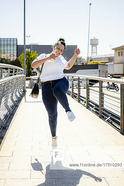 Carefree curvy young woman jumping in the city