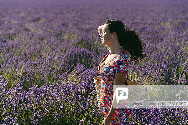 Portrait of beautiful woman standing in vast lavender field with hand in hair