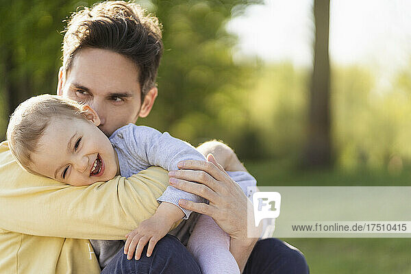 Vater und kleine Tochter kuscheln in einem Park