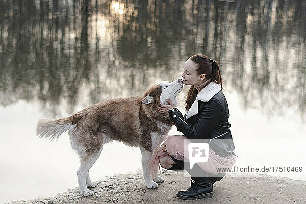 Young woman with playing with a husky near the river