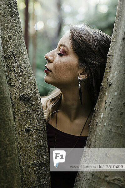 Portrait of young woman with closed eyes at tree