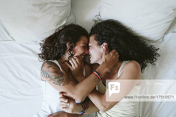 Happy lesbian couple romancing while lying on bed at home