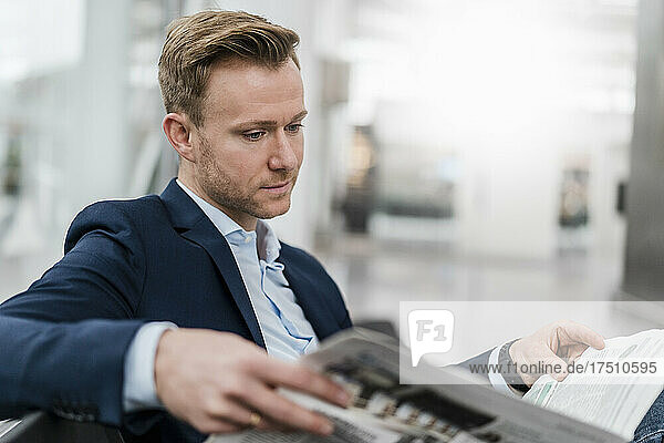 Confident businessman reading newspaper while sitting in city