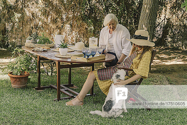 Mother and daughter with dog relaxing in picnic at yard