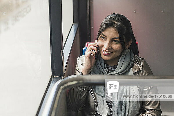 Smiling woman talking on mobile phone while traveling in bus