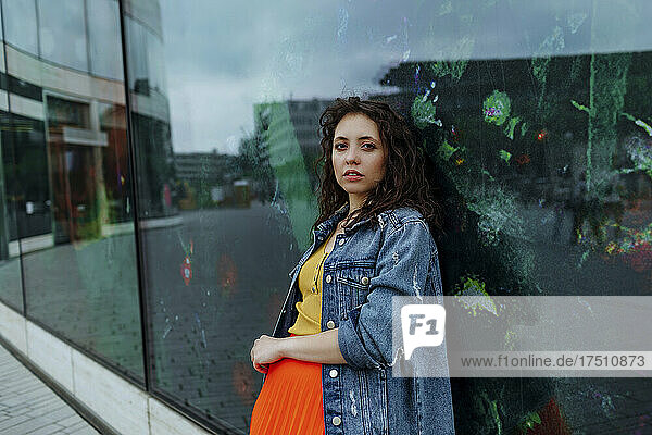 Young smiling woman leaning on glass wall