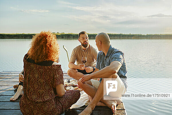 Friends having picnic on jetty at a lake