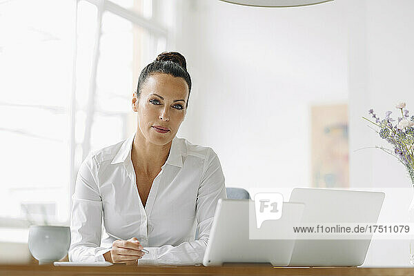 Confident businesswoman with laptops on desk working in home office