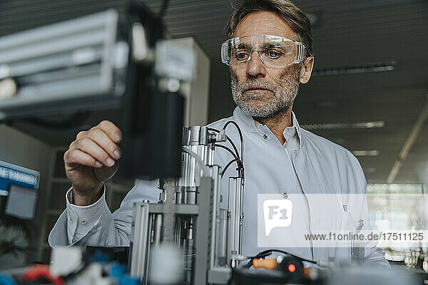 Männlicher Wissenschaftler mit Schutzbrillen-Untersuchungsgerät im Labor