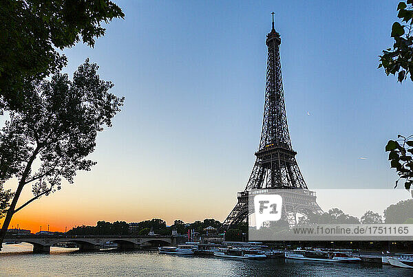 Eiffel Tower by seine river against clear sky at sunset  Paris  France