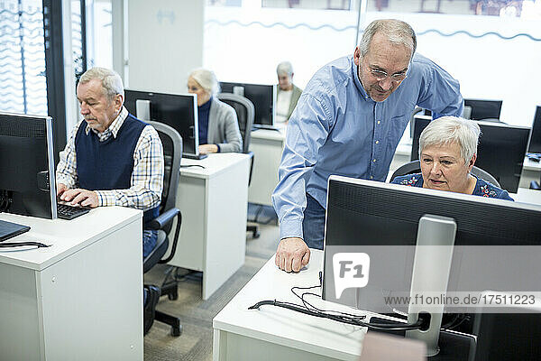 Active seniors attending computer course  intructor giving advice
