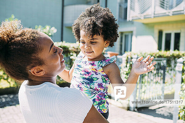 Nahaufnahme einer Mutter  die ihre süße Tochter trägt  während sie an einem sonnigen Tag im Freien steht