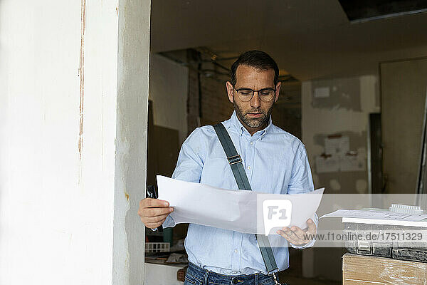 Architect studying plan in a house under construction