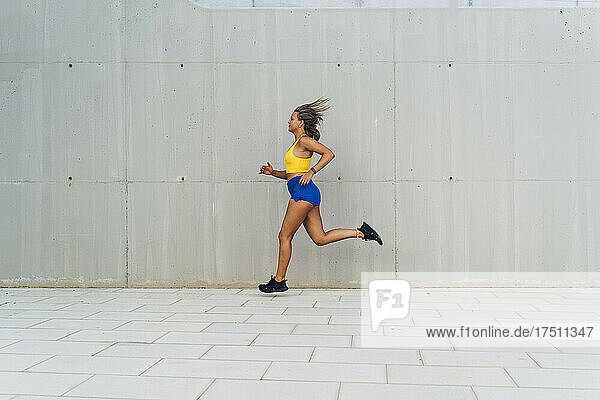 Female jogger in front of grey wall