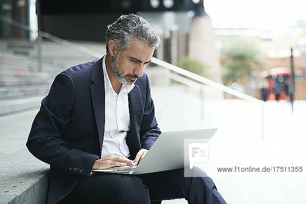 Businessman working on laptop in city