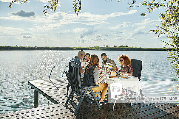 Friends having dinner on jetty at a lake