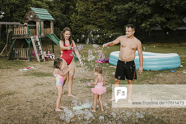 Happy family playing with soap bubbles in garden