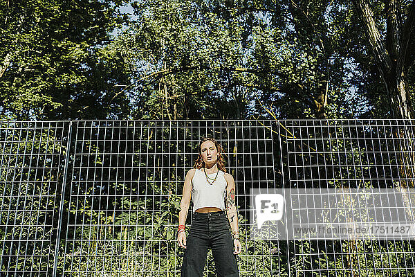 Woman standing against fence in city