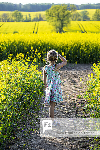 Girl standing in farm of rapeseed field